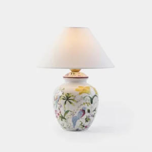 Botanical ceramic table lamp with hand-painted floral and bird design on white porcelain base with off-white tapered fabric shade, studio front view