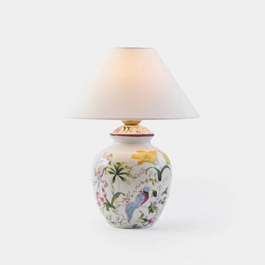 Botanical ceramic table lamp with hand-painted floral and bird design on white porcelain base with off-white tapered fabric shade, studio front view