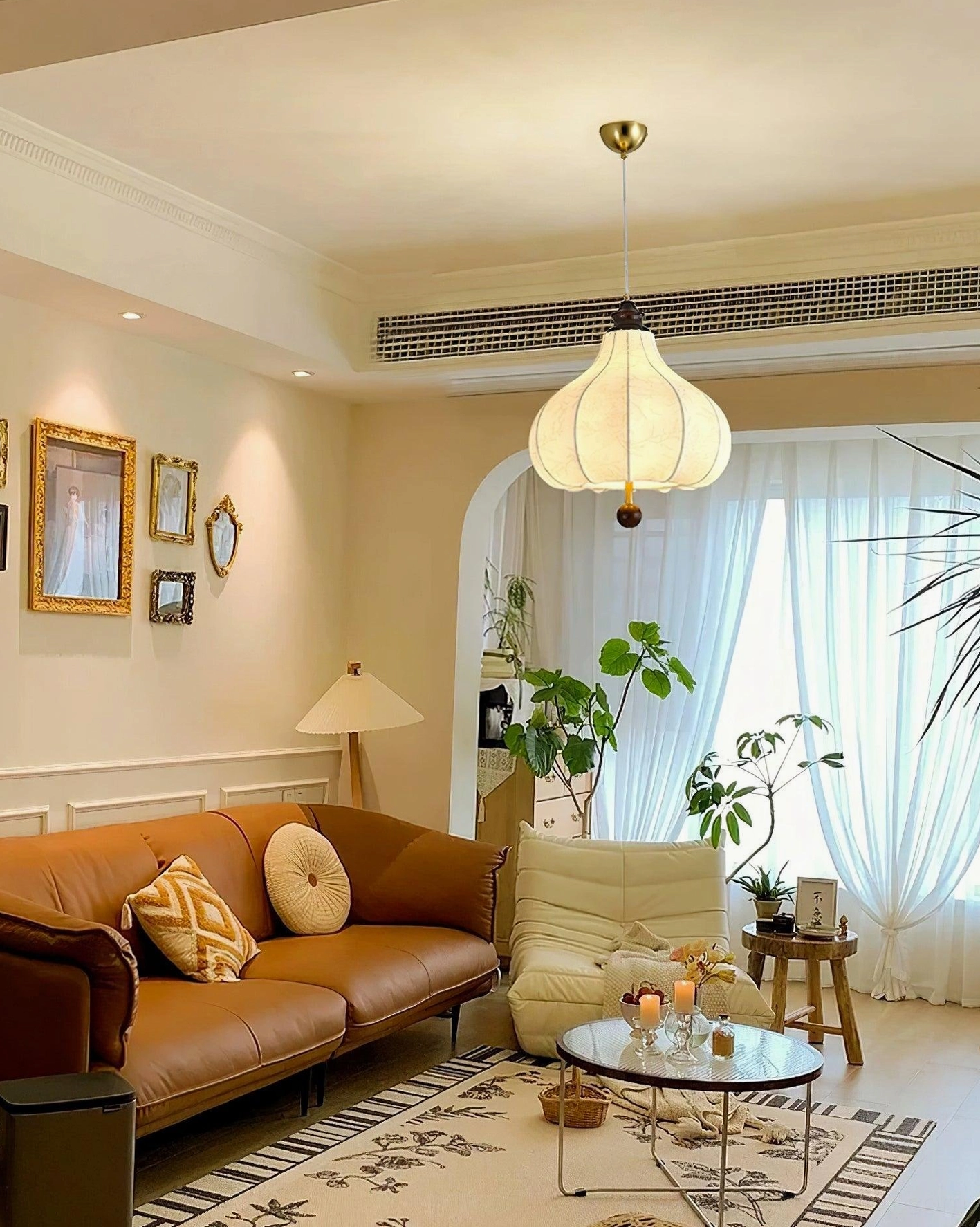 Off-white ribbed fabric pendant lamp with subtle floral print in retro living room with leather sofa, soft warm lighting