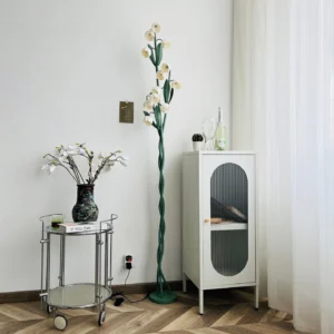 Modern botanical floor lamp in small living room corner with metal trolley cart and white storage cabinet, lifestyle interior design shot