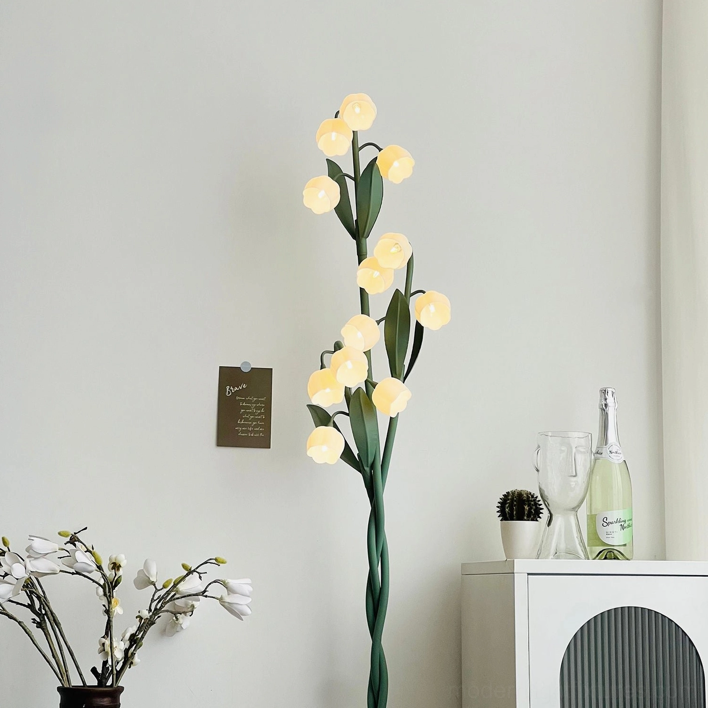 Three-light floor lamp in room setting demonstrating warm diffused light and botanical design aesthetic