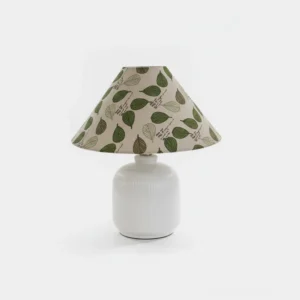Botanical floral table lamp with white ribbed ceramic base and green leaf printed fabric shade, front view on white background