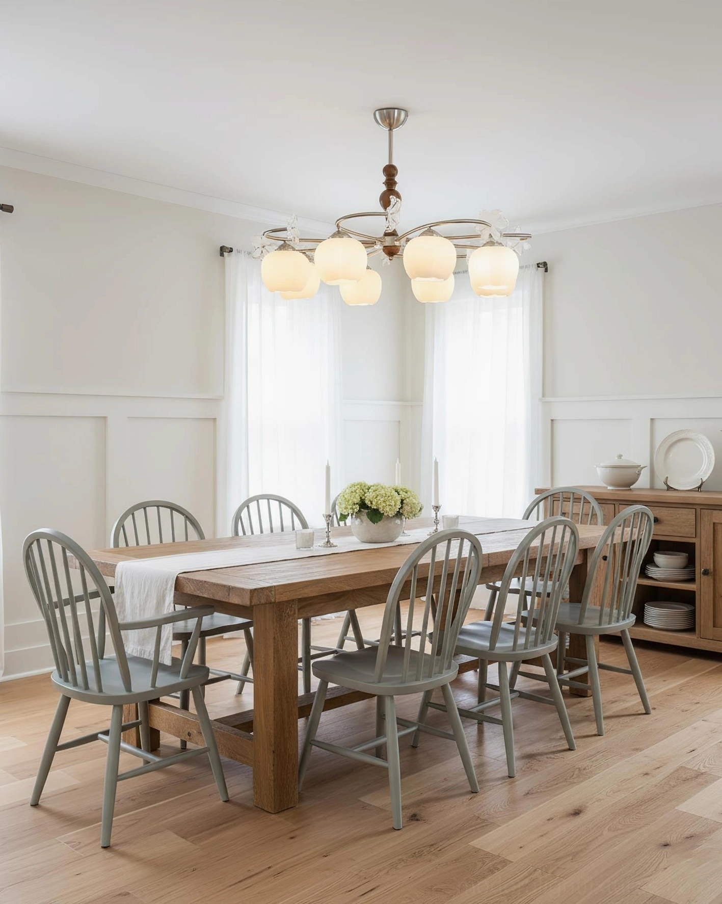 Modern farmhouse chandelier illuminated above wooden dining room table with rustic decor and warm ambiance