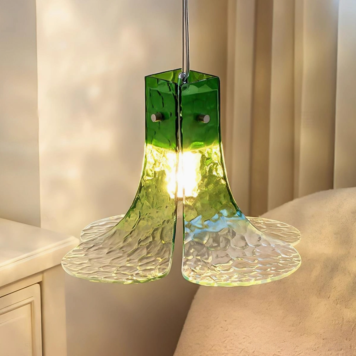 Illuminated hand-blown glass botanical pendant light casting warm amber glow in cozy living space