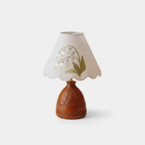 Botanical embroidered table lamp with carved wooden base and scalloped beige shade featuring lily motifs