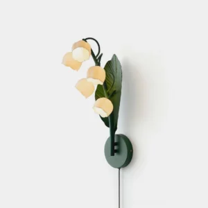 Botanical wall sconce with lily of the valley design in green and white, frontal view on white wall