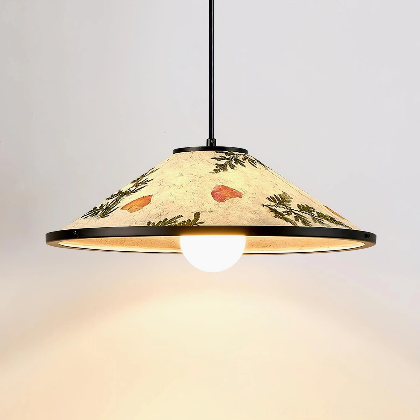 Botanical pendant lamp in black metal frame with natural dried leaves creating warm ambient light