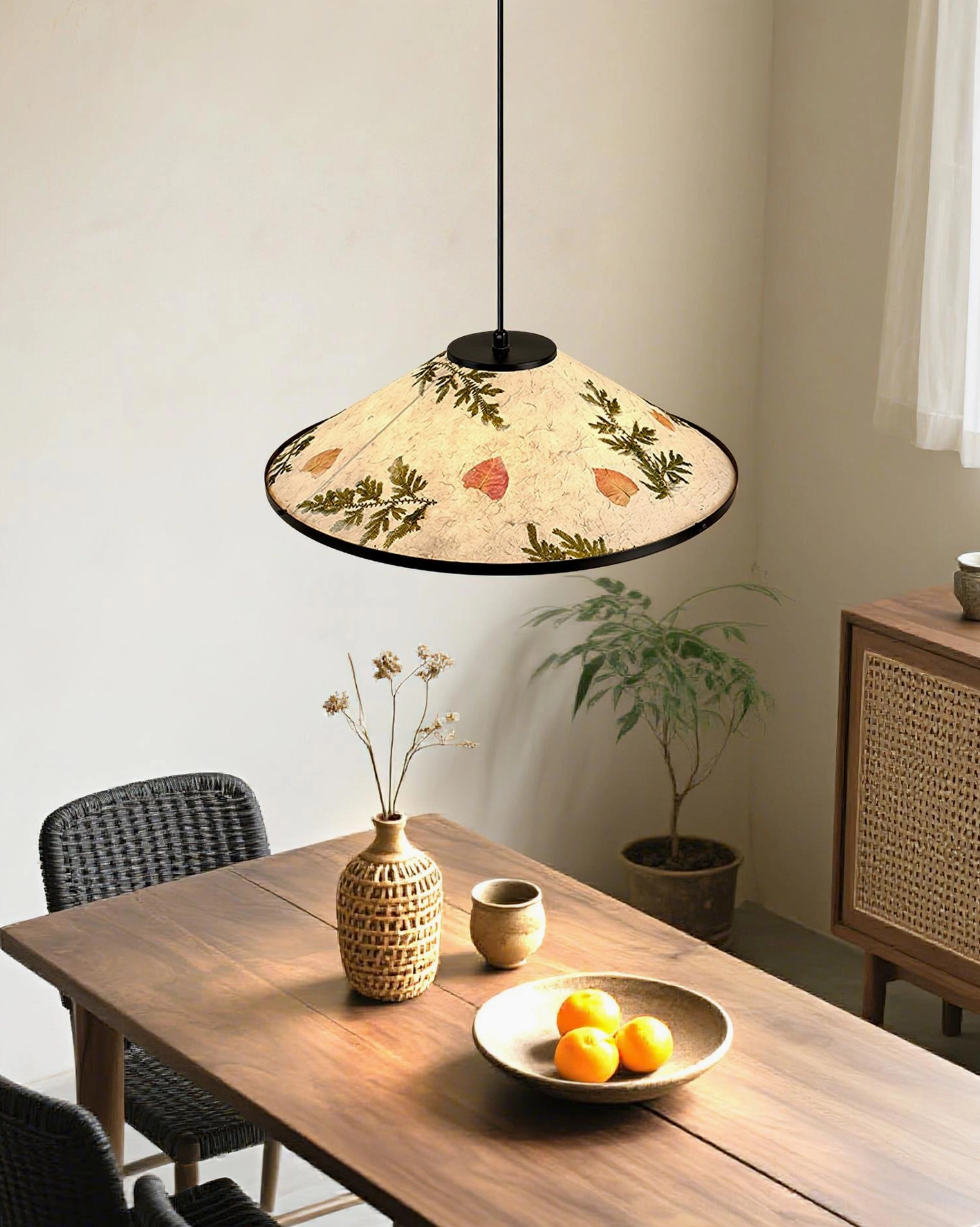 Modern botanical pendant lamp hanging above wooden dining table with tableware in home dining room setting