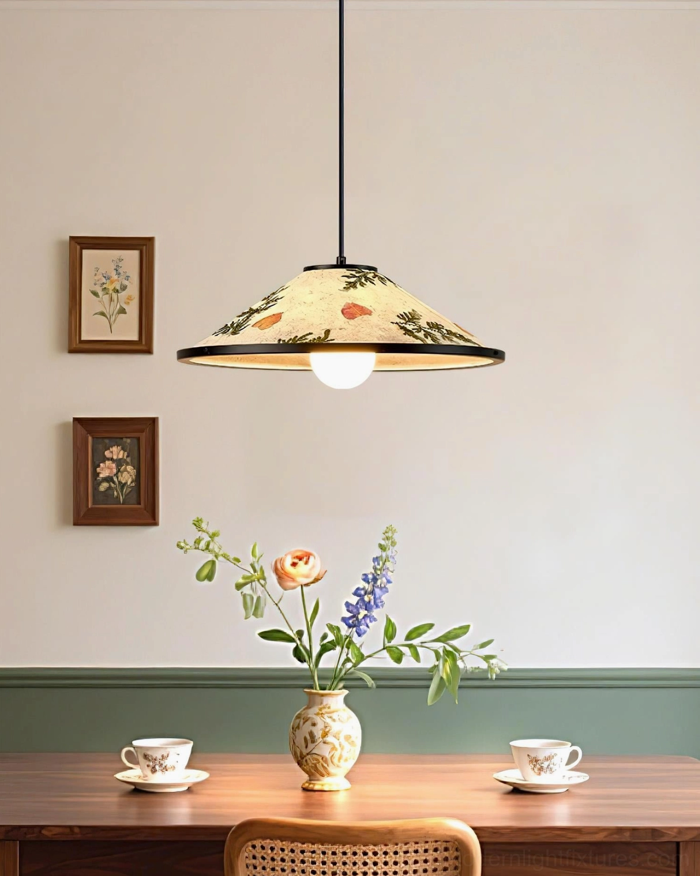 Vintage style botanical pendant lamp hanging above long wooden dining table with tableware and wall art
