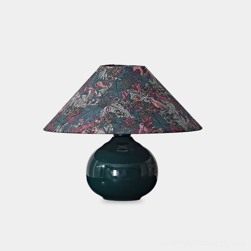 Botanical ceramic table lamp with forest green glossy base and intricate botanical fabric shade featuring wildlife patterns - studio view