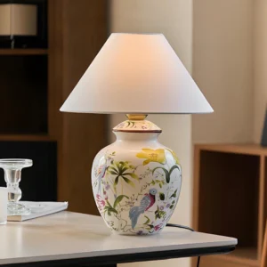 Modern botanical table lamp displayed on home desk with hand-painted ceramic base and fabric lampshade, three-quarter angle view