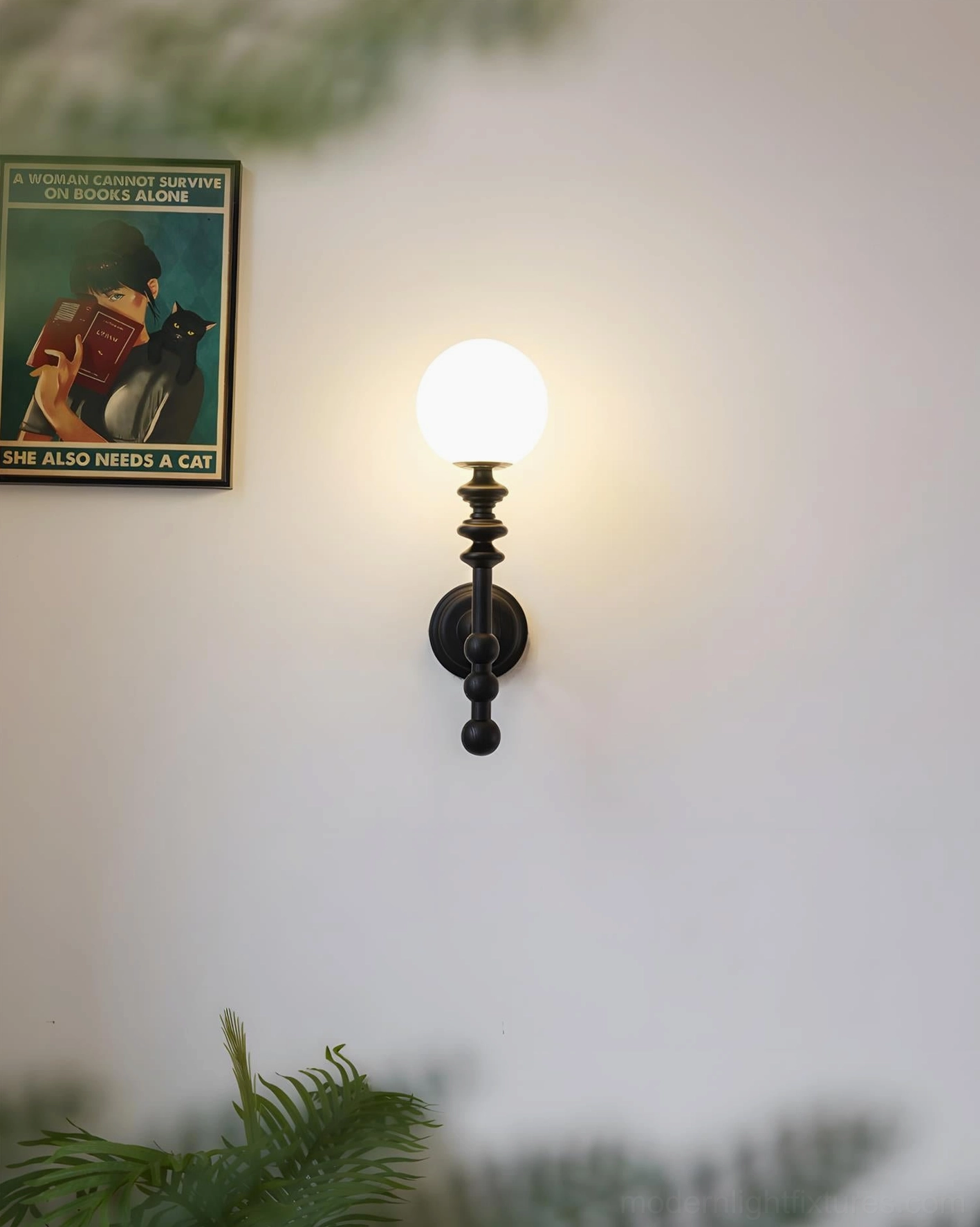 Matte black Bouton wall lamp installed beside vintage poster creating dramatic ambient lighting effect