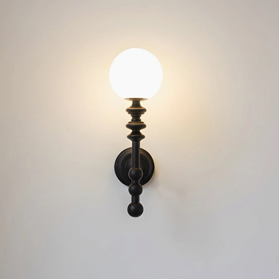 Black Bouton minimalist wall sconce with matte finish and frosted glass sphere on plain wall