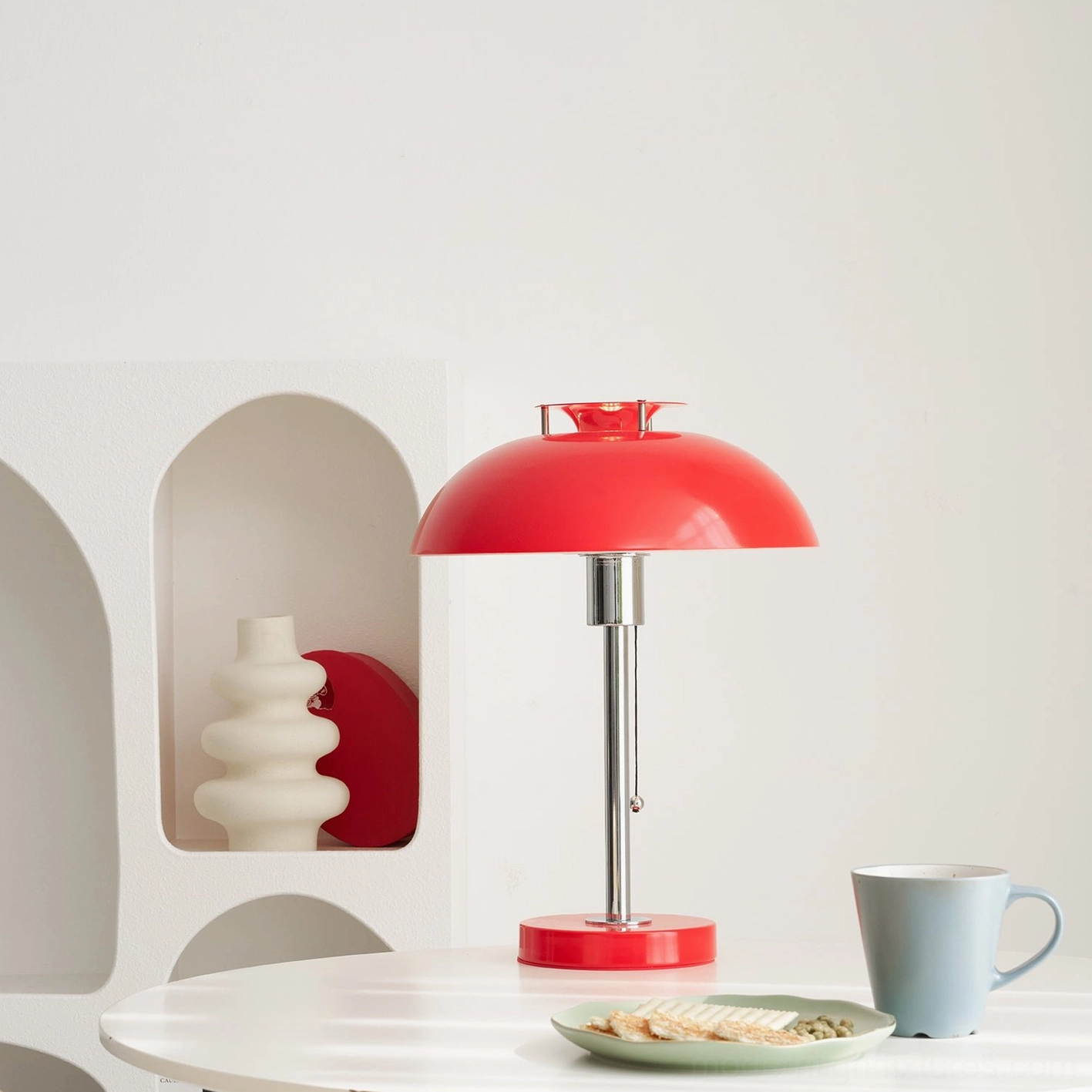 Red Bowie metal table lamp three-quarter front view on white dining table with matching red base and shade