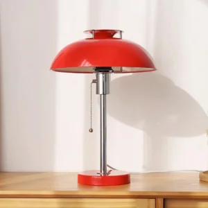 Red metal Bowie table lamp three-quarter view showing chrome stem and pull-chain switch detail on wooden side table