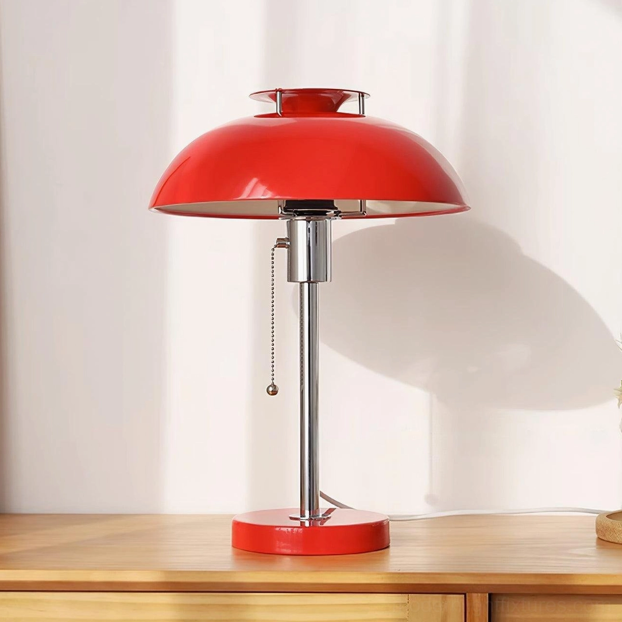 Red metal Bowie table lamp three-quarter view showing chrome stem and pull-chain switch detail on wooden side table