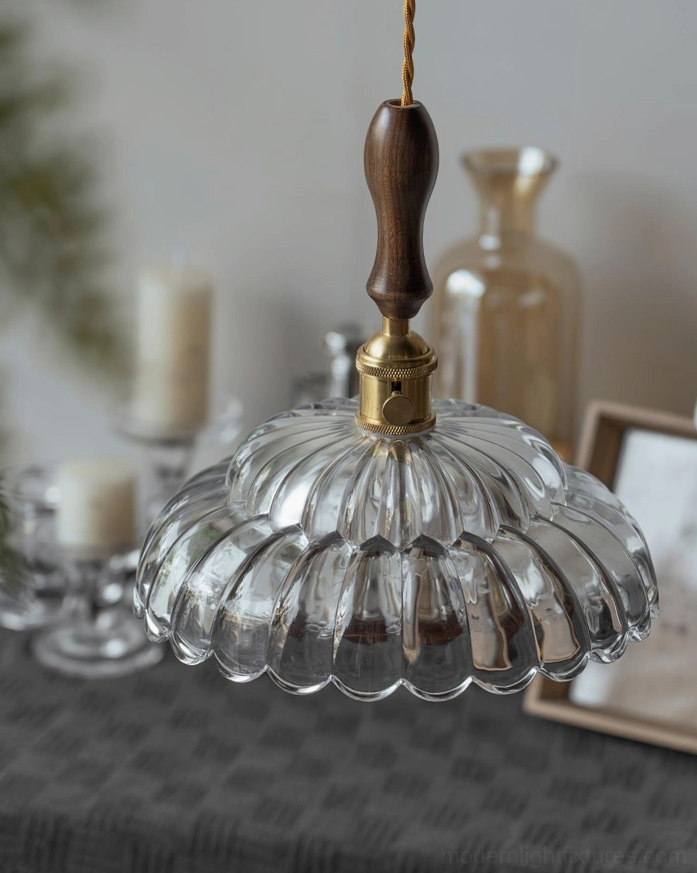 Large scalloped glass pendant shade with brass hardware, three-quarter view with candles and glassware