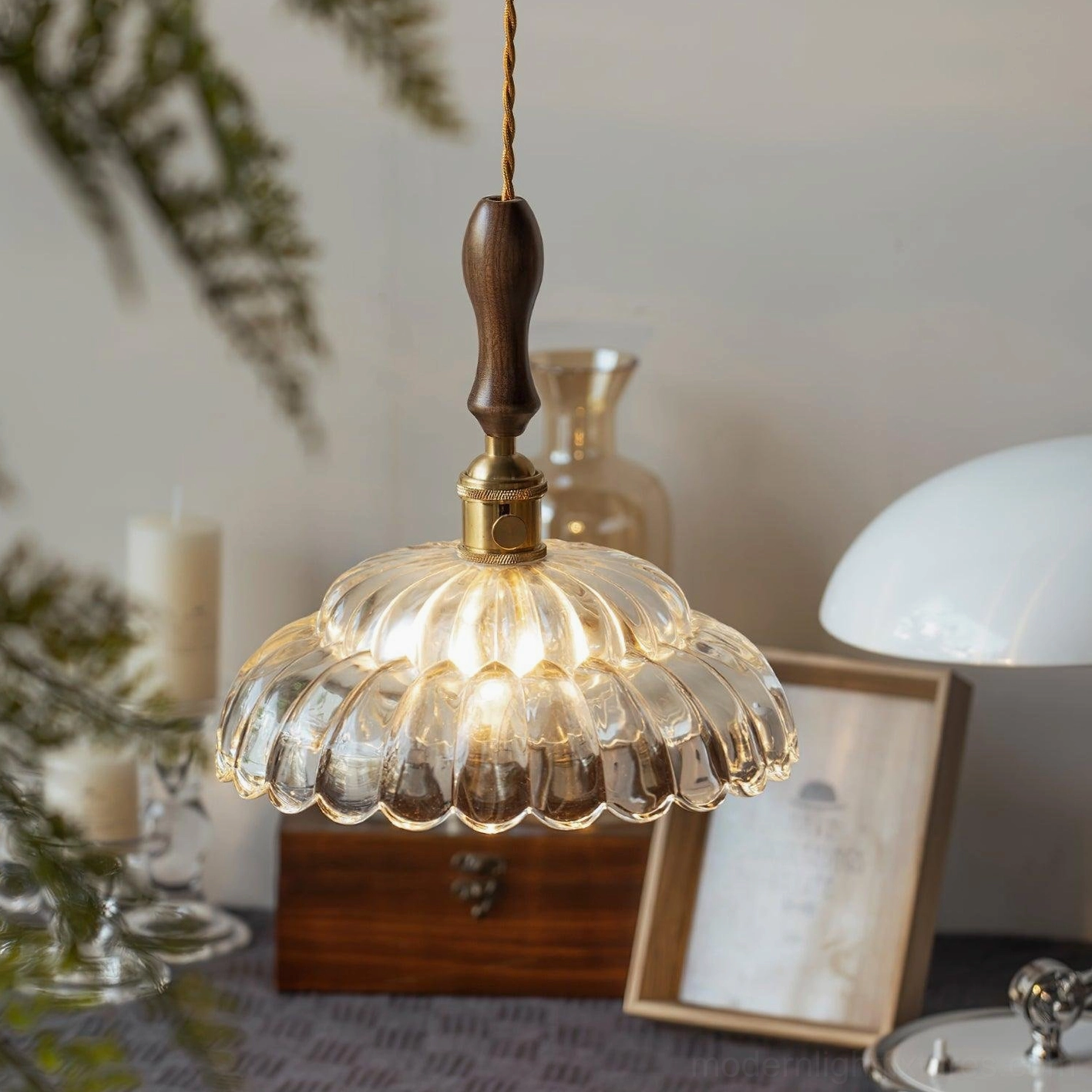 Clear scalloped glass pendant lamp with ambient lighting, side view with decorative tabletop setup