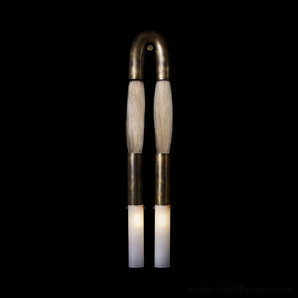 Branwick modern wall sconce illuminated against black background, showing warm ambient glow from glass diffusers and aged brass finish