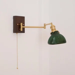 Adjustable swing arm wall lamp with brass finish and dark walnut wood plate, three-quarter angle view