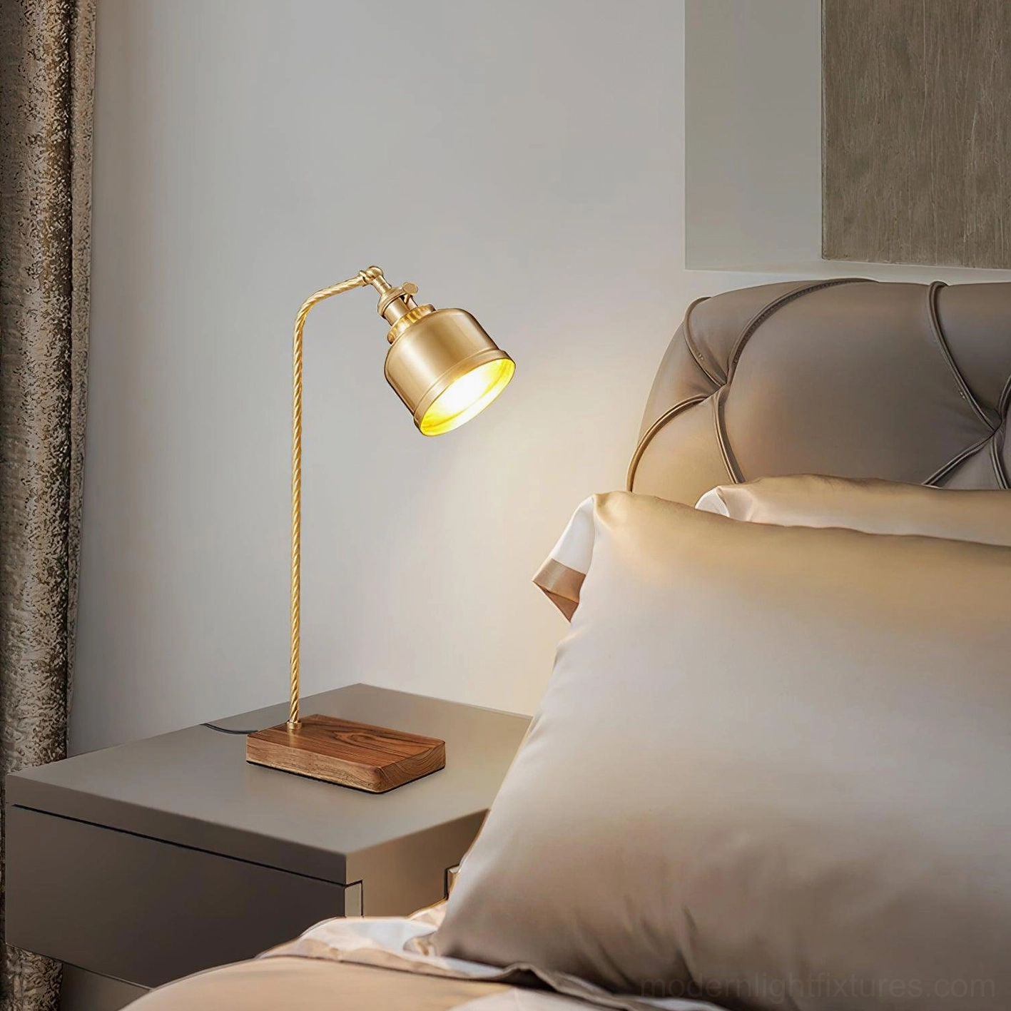 Gold brass table lamp with twisted metal arm and walnut wood base on modern bed side table