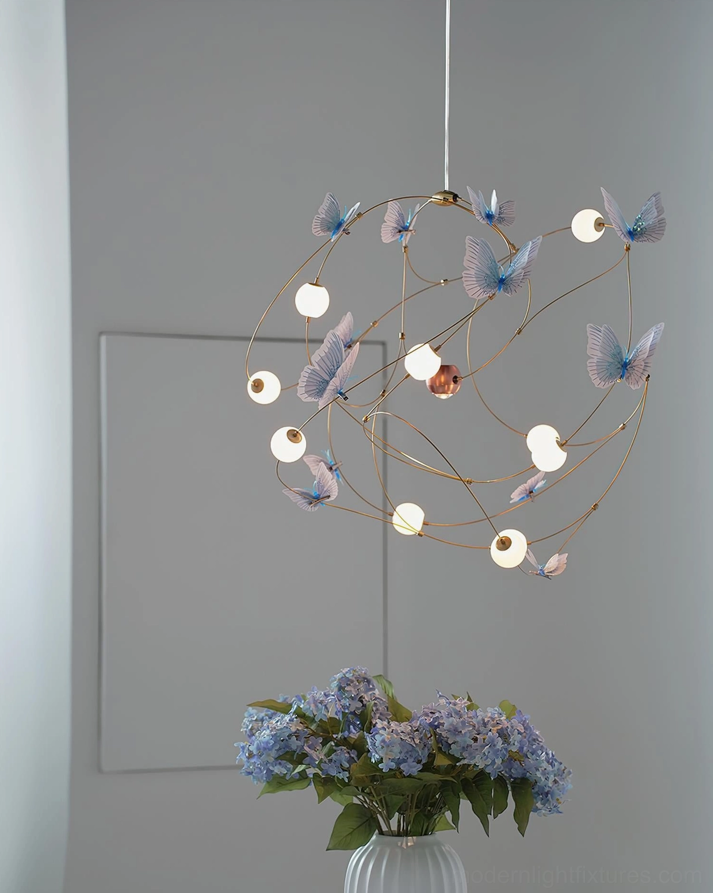 Brass butterfly pendant chandelier with translucent acrylic shades demonstrating sculptural artistic design and warm ambient glow