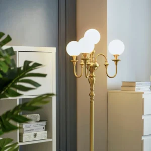 Brass candelabra floor lamp in modern living room corner, three-quarter front angle showing elegant curved arms and glass globe shades