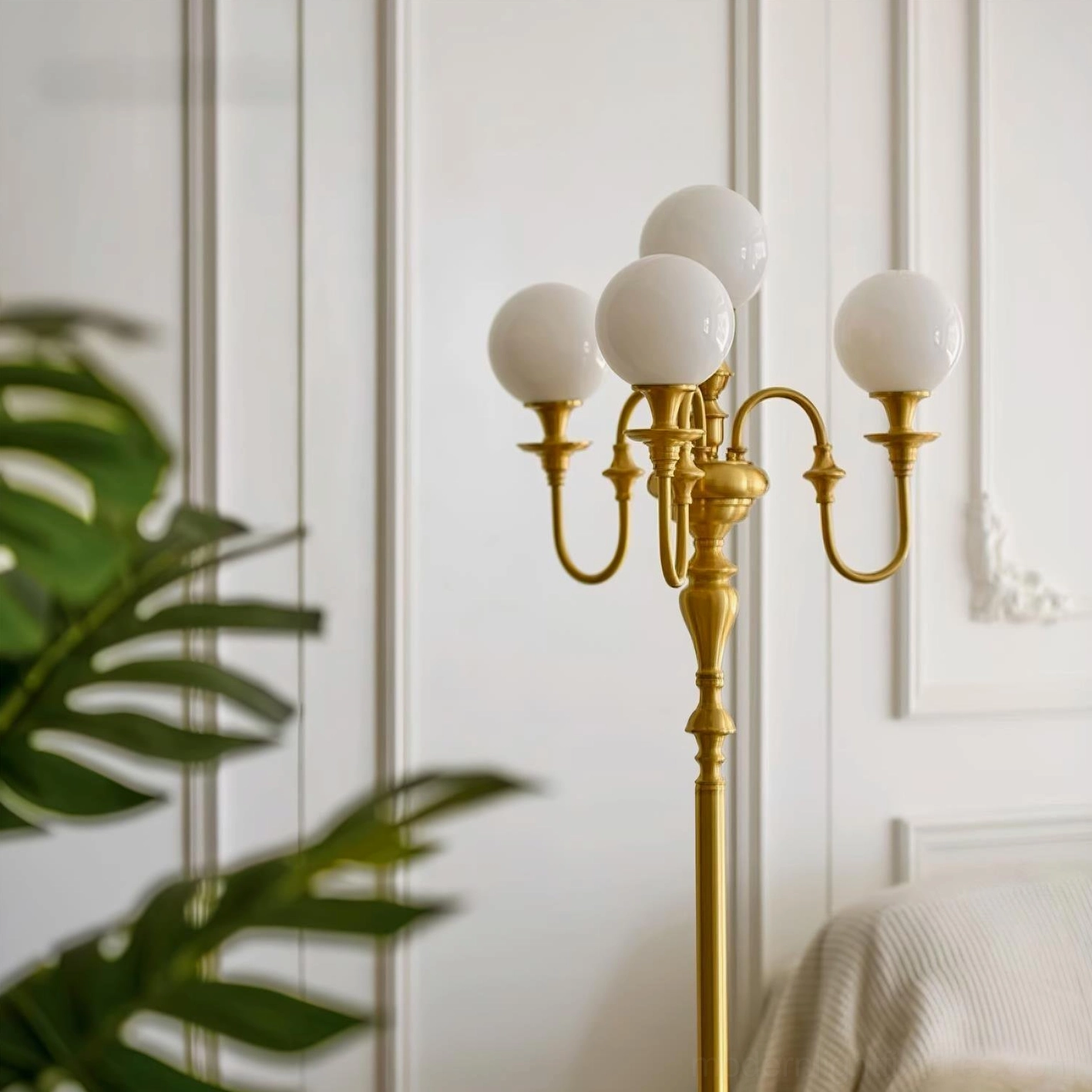 Close-up side view of brass candelabra floor lamp in elegant bedroom with wainscot walls, curved metal arms detail