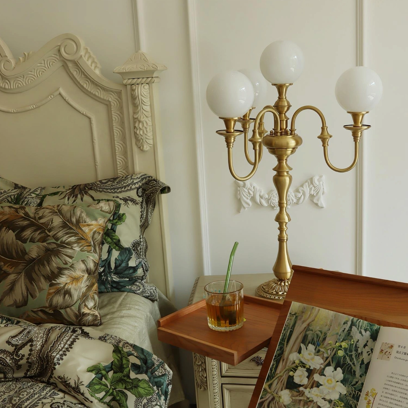 Modern brass 5-head candlestick table lamp on master bedroom bedside table with botanical decor
