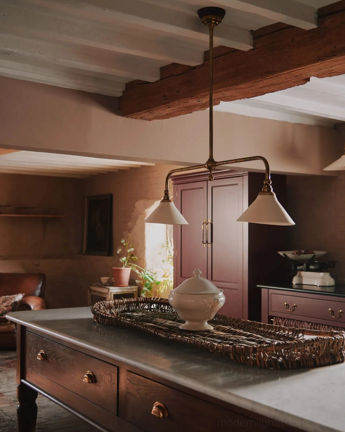 Aged brass two-head pendant chandelier in rustic kitchen with wooden beam ceiling and off-white ceramic lamp shades