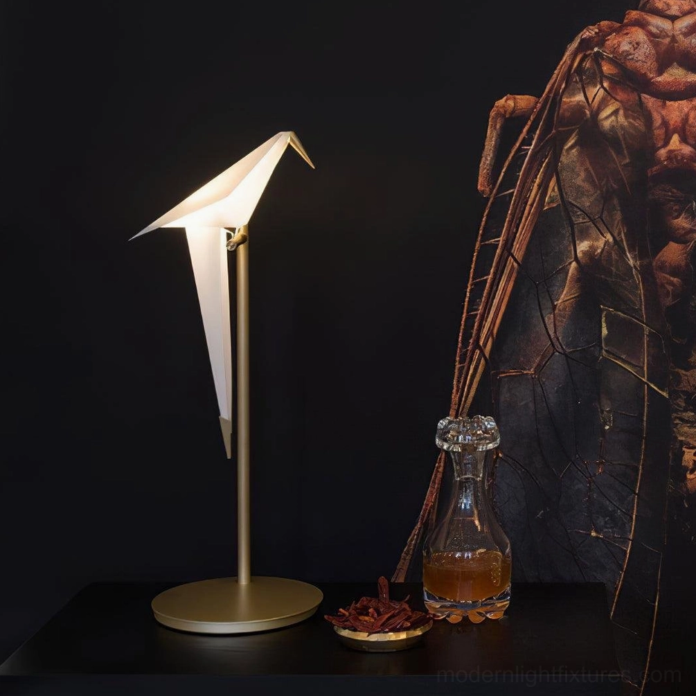 Illuminated origami crane table lamp on dark luxury side table with warm LED light and insect art