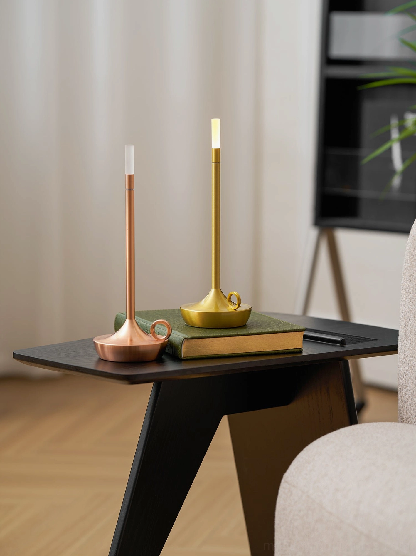 Brass gold minimalist LED table lamp on modern side table with book and decorative metal cup, three-quarter view