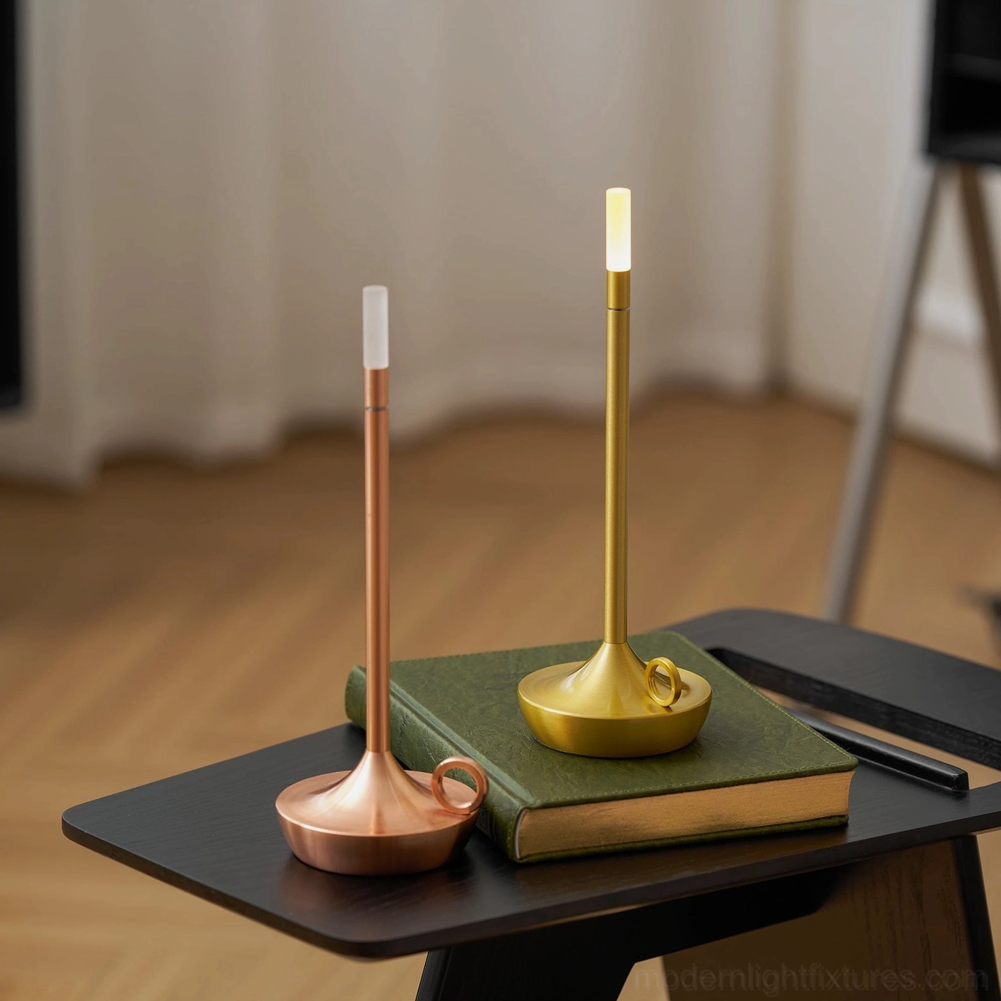Two minimalist LED table lamps in brass gold and rose gold finishes on living room side table with book decor