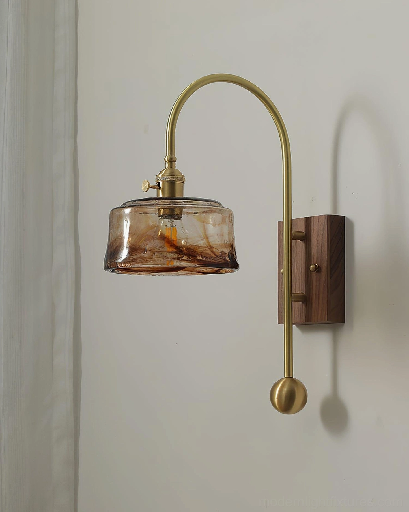 Industrial wall sconce featuring smoked amber glass dome shade with brass hardware and walnut mount