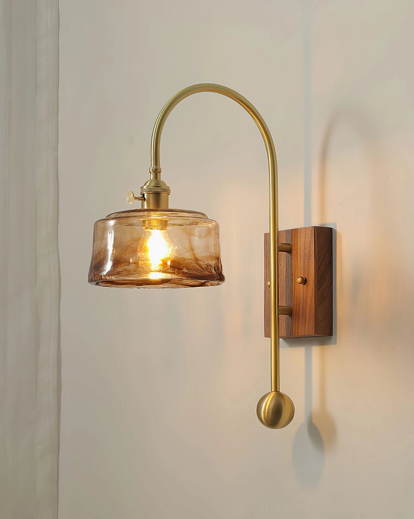Textured amber glass wall sconce with brass gooseneck arm and walnut wall mount