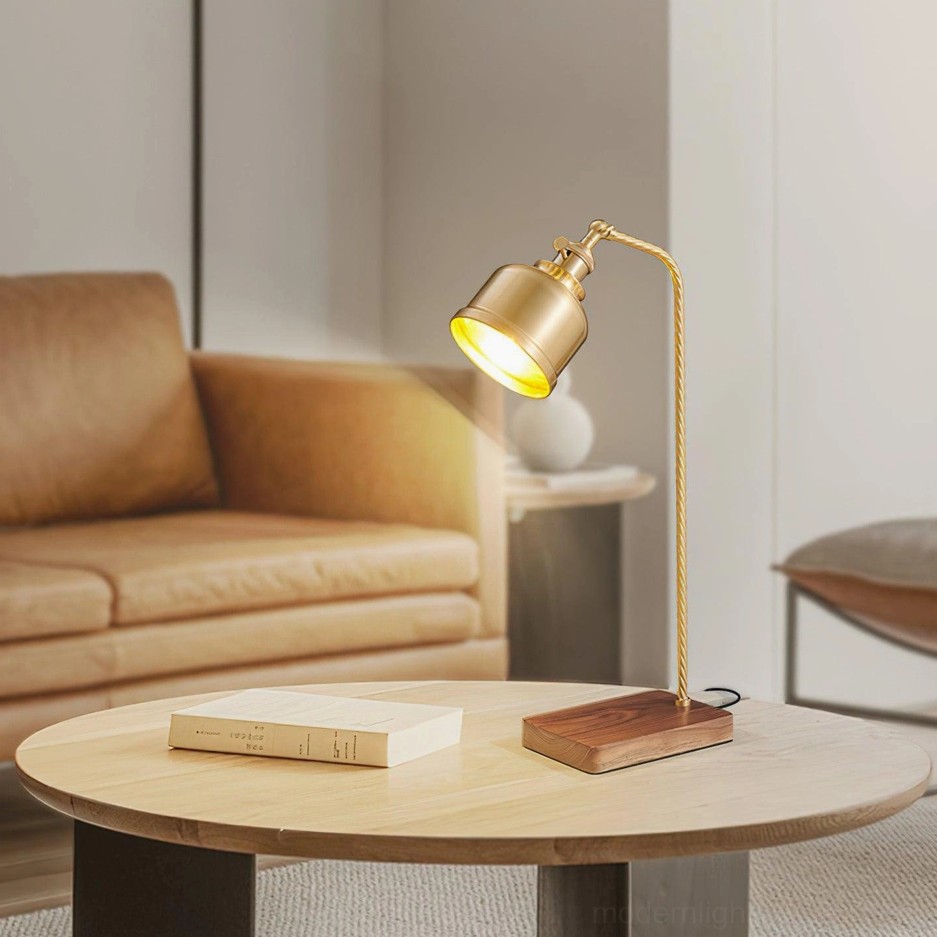 Modern brass industrial desk lamp with cylindrical shade and walnut wood base near tan leather sofa