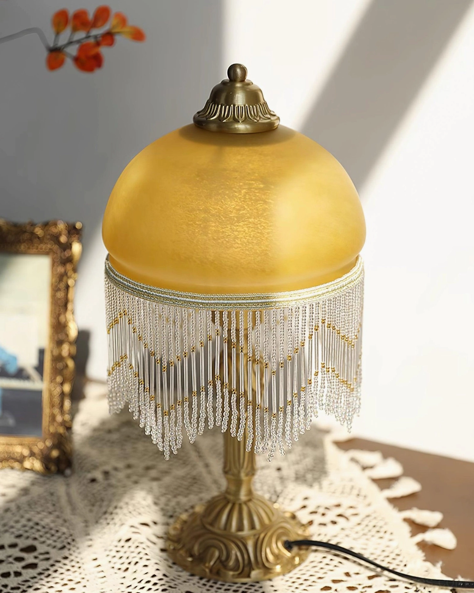 Vintage brass table lamp right side view showing ornate carved base with crystal beaded tassel and amber dome shade