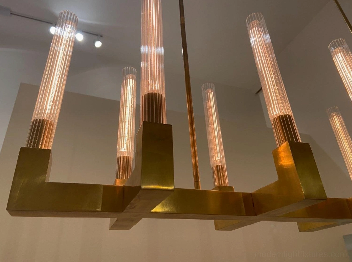 Modern linear branch-style brass chandelier close-up ribbed glass shade detail