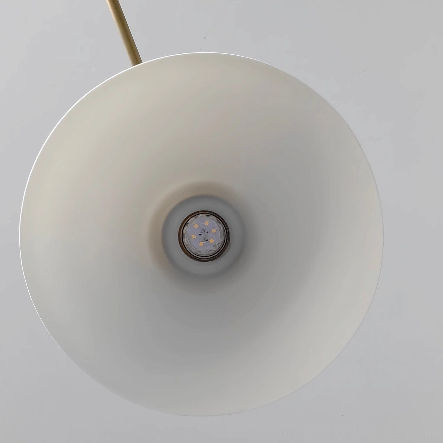 Brass metal linear pendant with white ceramic shades installed in kitchen window area with natural daylight ambiance