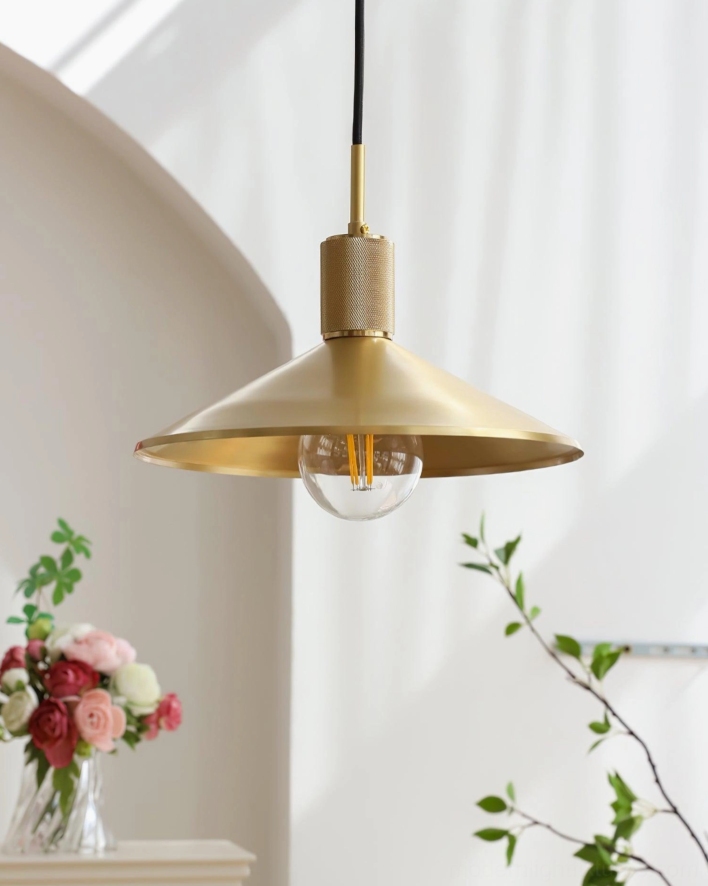 Brass pendant fixture with black hanging cord and wide conical shade creating downward focused lighting