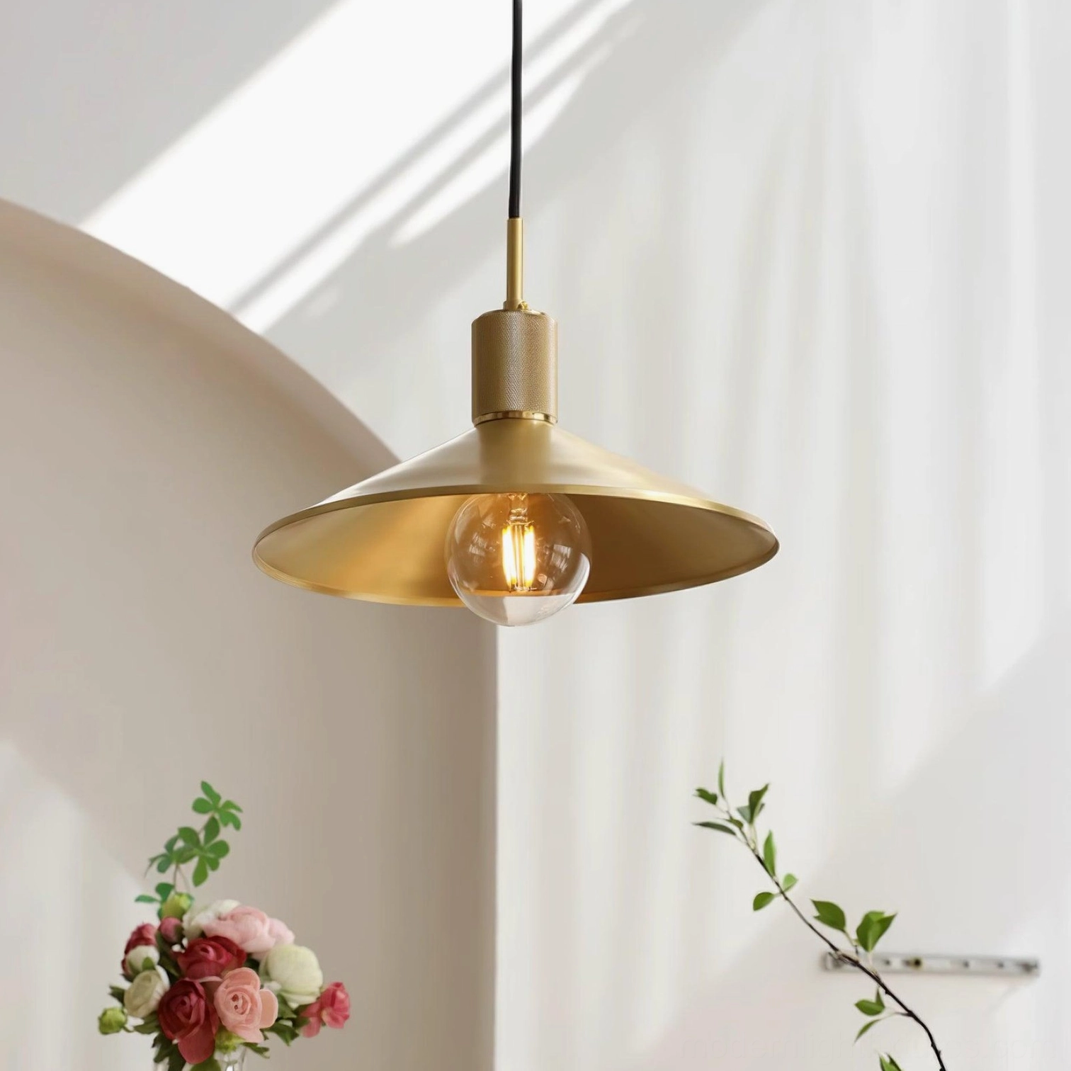 Classic brass pendant lamp 3/4 angle with knurled metal top and decorative exposed bulb in cozy interior setting