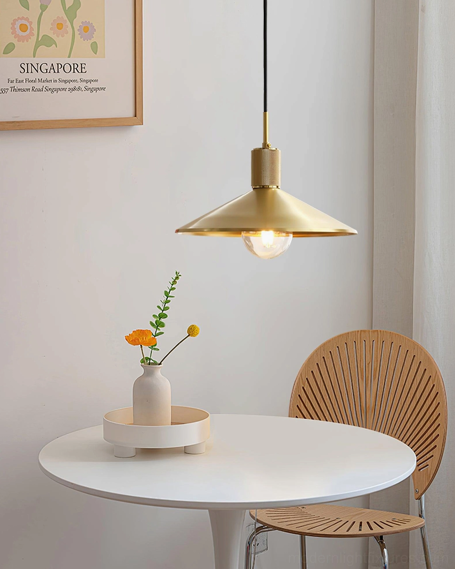 Brass pendant light suspended above round white dining table in modern small dining nook setting