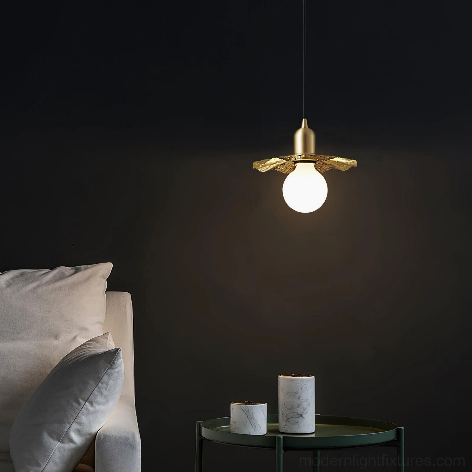 Gold brass petal pendant lamp with exposed bulb suspended in modern living room with dark walls