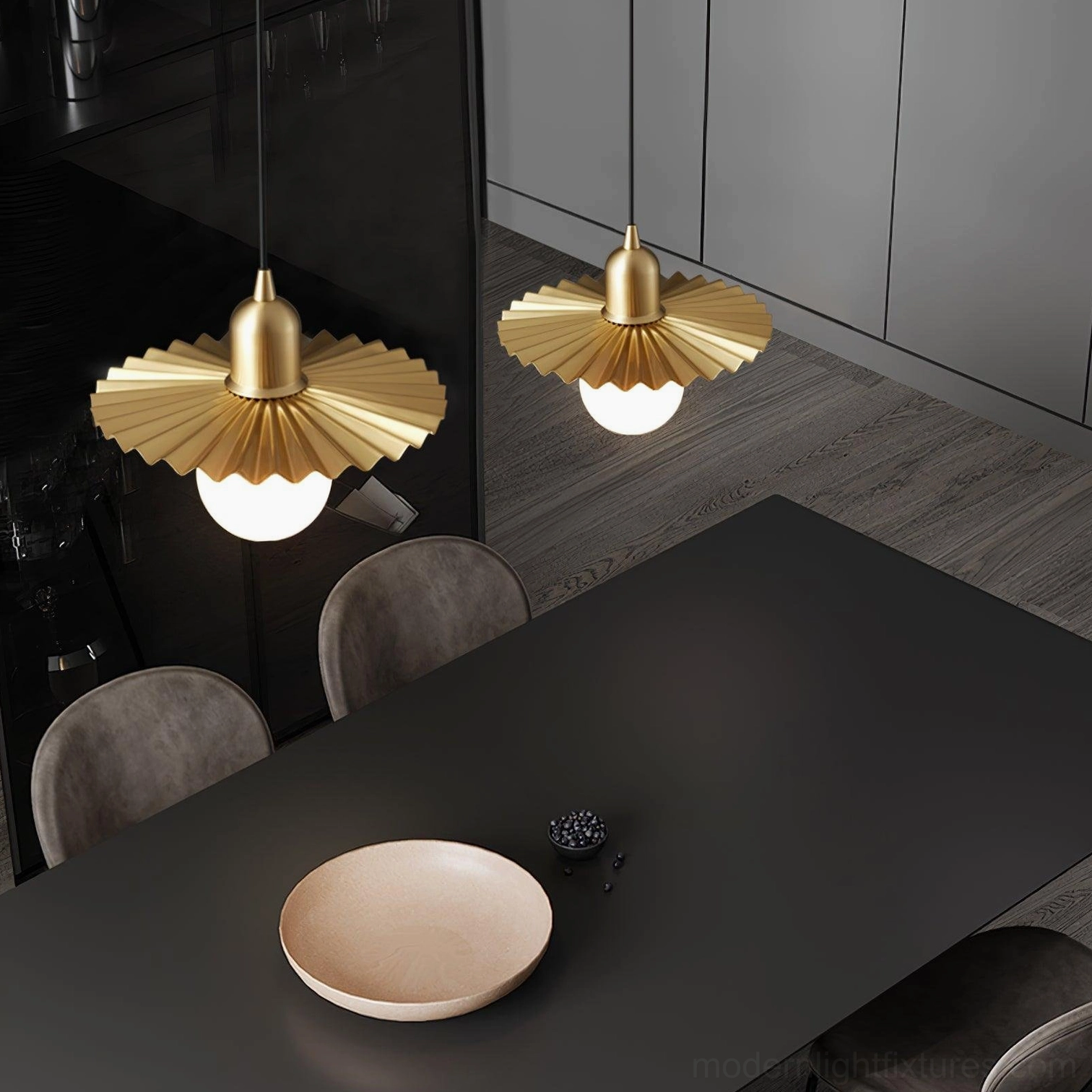 Modern brass pendant lights with pleated gold shades installed above dining table in contemporary dark interior