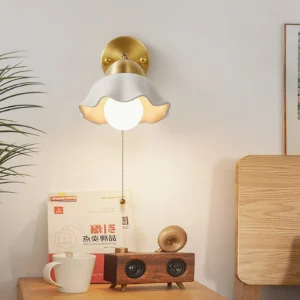 Modern brass wall sconce with floral ceramic shade paired with decorative home accessories - styled vignette