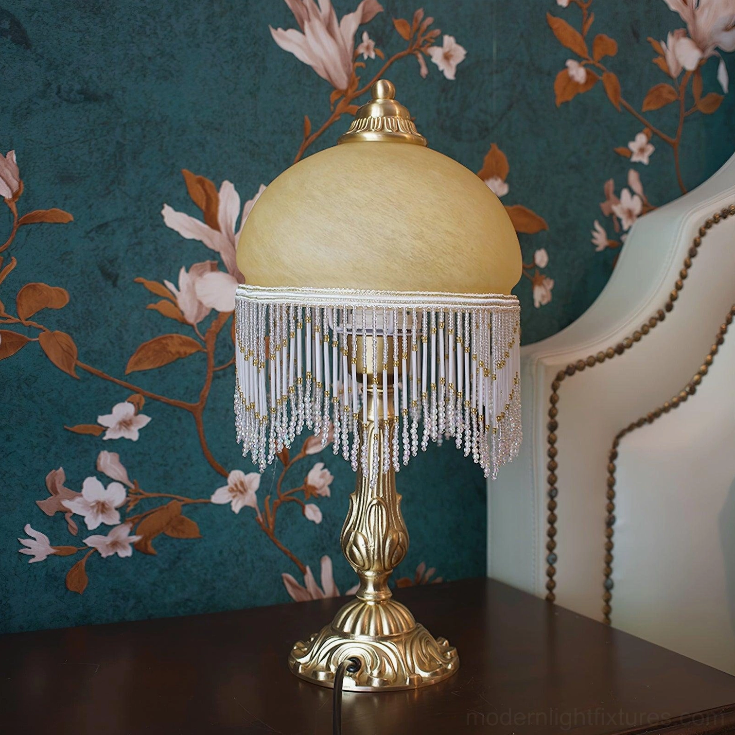 Vintage brass tassel table lamp showing intricate carved pedestal base and warm glowing amber glass shade