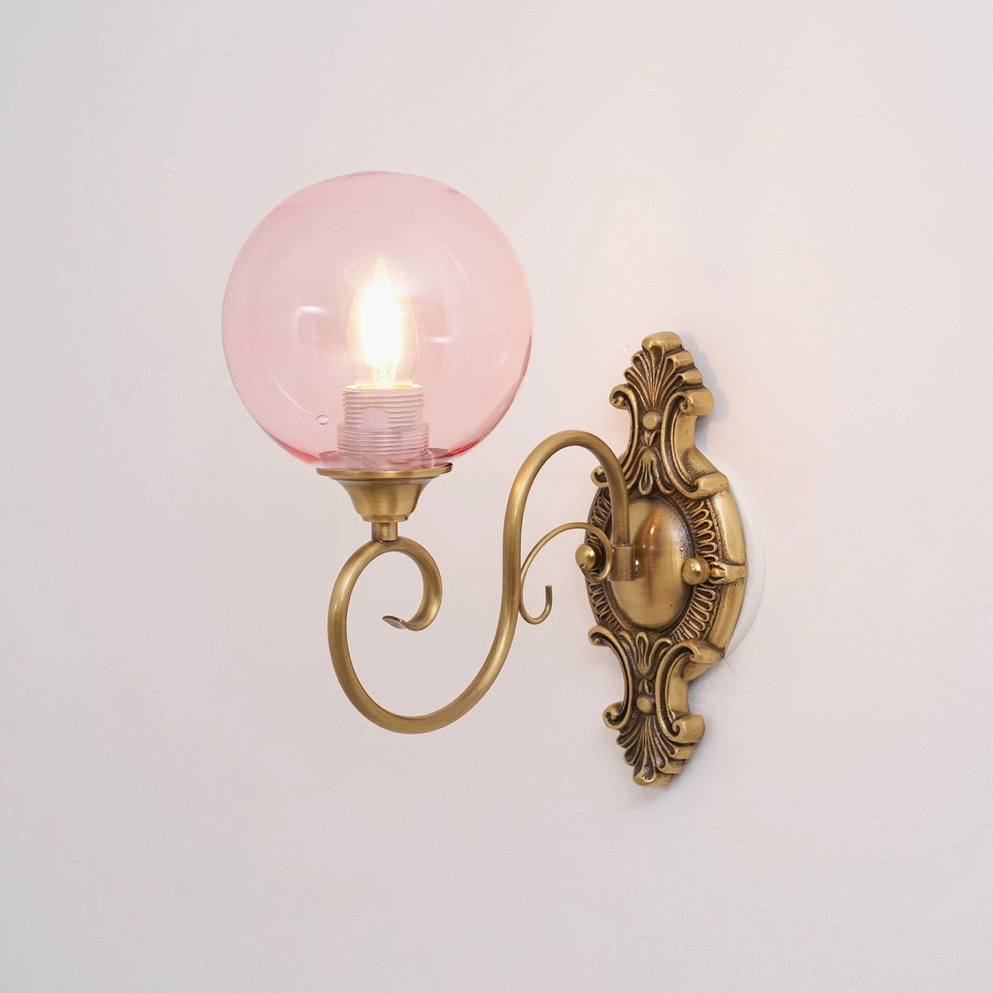 Ornate brass wall sconce detail shot, baroque backplate and curved metal arm close-up