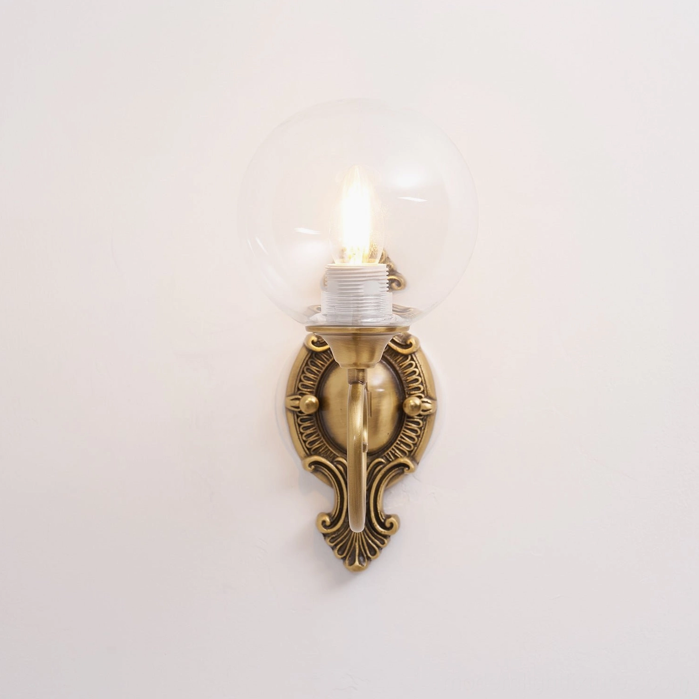 Close-up detail of ornate brass wall sconce glass globe and metal coupling, architectural fixture