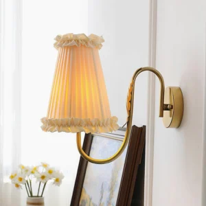 Illuminated brass wall sconce with ruffled pleated shade in home interior setting