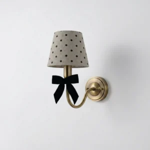 Vintage polka dot wall lamp with elegant black ribbon bow detail, brass curved arm fixture, direct frontal view on white background